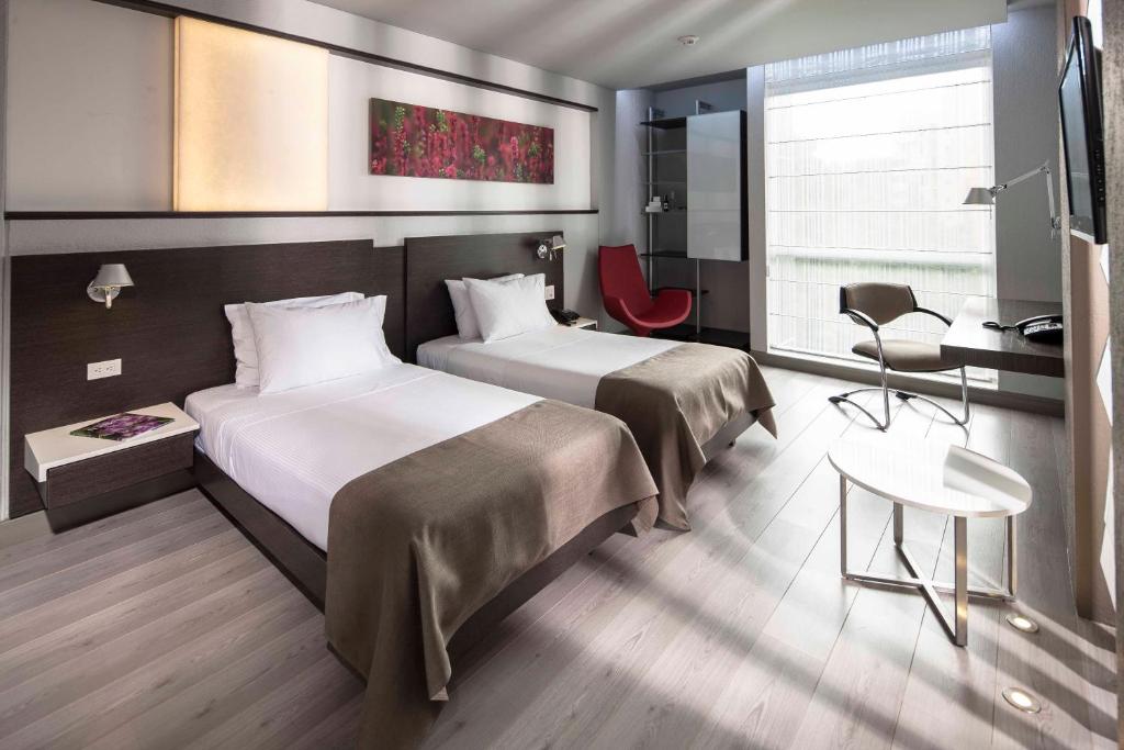 Cette chambre comprend deux lits et un bureau. dans l'établissement Inntu Hotel, à Medellín