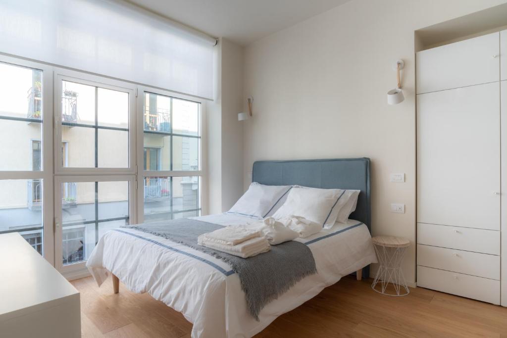 a white bedroom with a bed and a large window at Mini loft Moscova in Milan