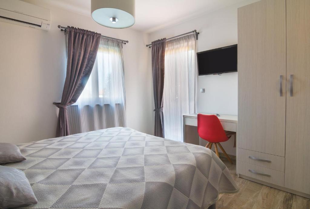 a bedroom with a bed and a desk and a window at Alison Apartments in Premantura