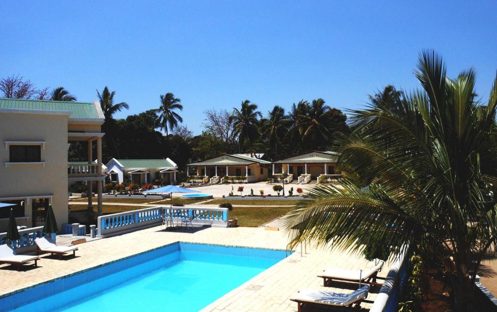 uma piscina com uma palmeira ao lado de uma casa em SAARA HOTEL em Mahajanga
