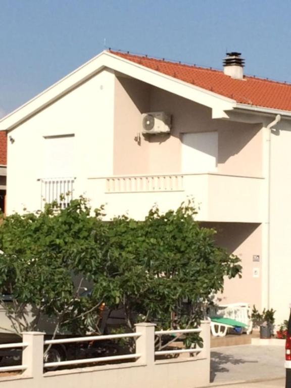 ein weißes Haus mit einem Baum davor in der Unterkunft S&M Apartments in Drače