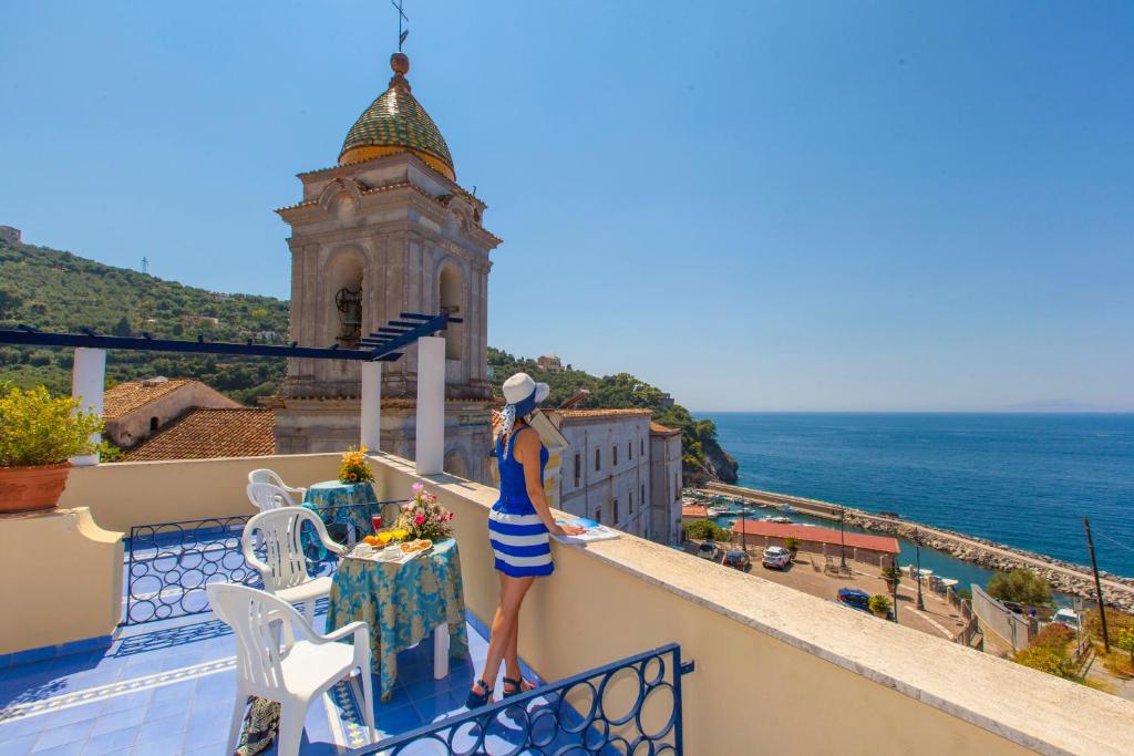 Eine Frau steht auf einem Balkon mit Meerblick in der Unterkunft Hotel Piccolo Paradiso in Massa Lubrense