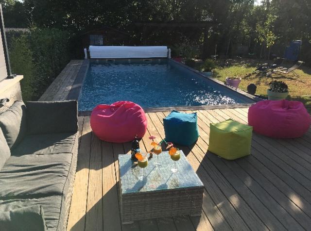 einen Pool mit zwei Ottomanen, einem Tisch und einer Bank in der Unterkunft Chez Stéphane et Emilie in Grenade-sur-Garonne