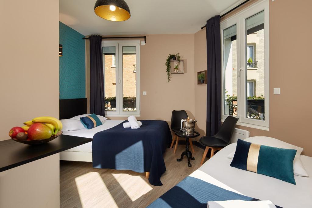 a room with two beds and a table with fruit on it at Résidence AURMAT - Appart - Hôtel - Boulogne - Paris in Boulogne-Billancourt