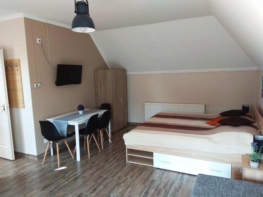 ハイドゥソボスローにあるÁlom Apartmanのベッドルーム1室(ベッド1台、テーブル、椅子付)