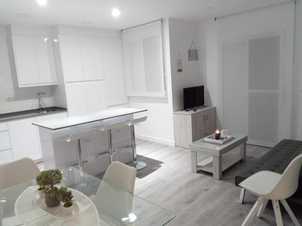 ein weißes Wohnzimmer mit einem Tisch und einem TV in der Unterkunft Beach House in Puerto de Mazarrón