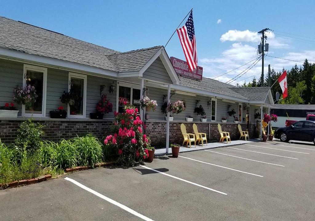 a building with chairs and an american flag in a parking lot at Fundy Rocks Motel in Hopewell Cape
