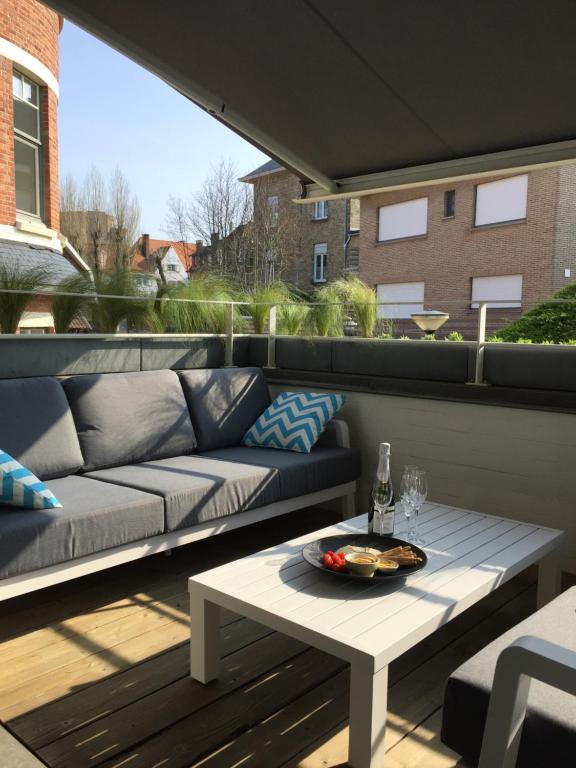 eine Terrasse mit einem Sofa und einem Couchtisch in der Unterkunft Vakantiewoning De Konijnenweg in De Panne