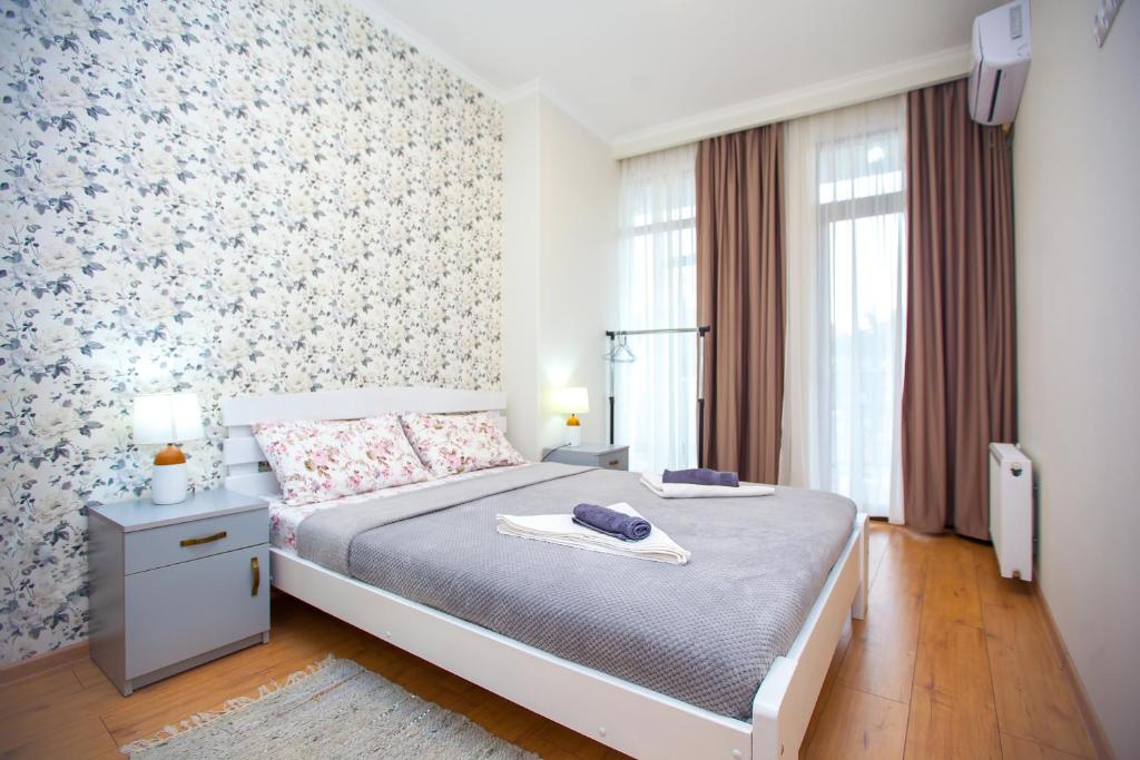 - une chambre avec un lit et un mur fleuri dans l'établissement Artemida Apartment TBS, à Tbilissi