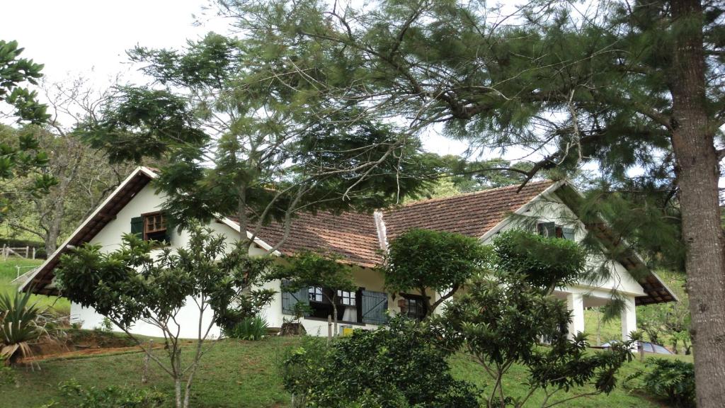a white house with trees in front of it at Sitio três porteiras in Paty do Alferes