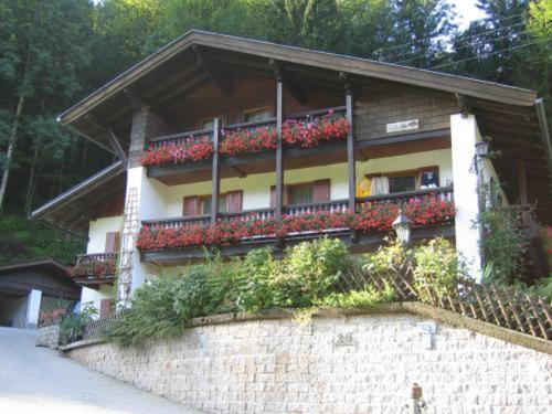 ein Gebäude mit roten Blumen auf den Balkonen in der Unterkunft Hotel Alpenresi in Ramsau bei Berchtesgaden