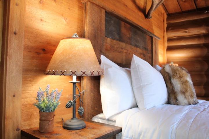 a bedroom with a bed and a lamp on a table at Elkhorn Cabins and Inn in West Yellowstone