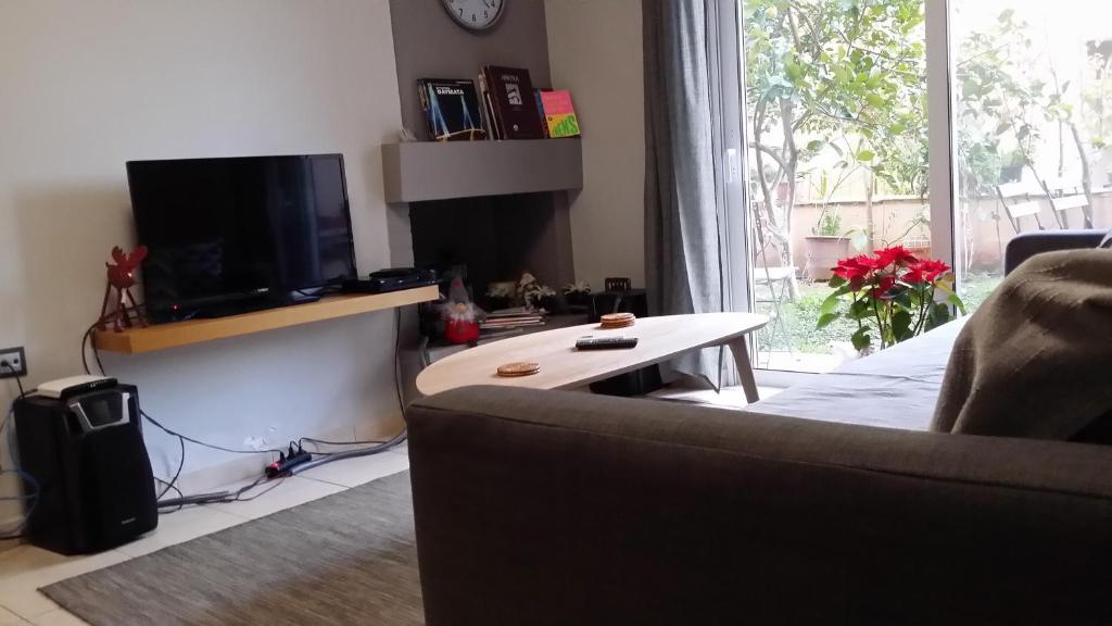 a living room with a couch and a tv and a table at Athenian apartment with garden, near metro station Chalandri Nu 3 in Athens