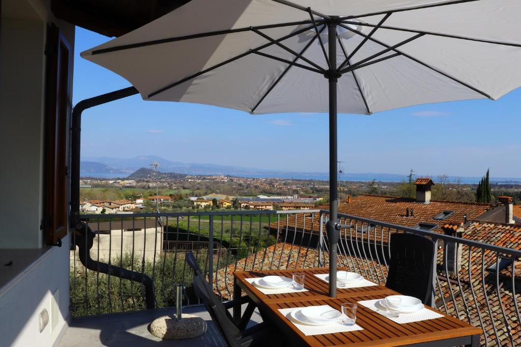 einen Tisch mit Sonnenschirm auf dem Balkon in der Unterkunft "Country House il Brolo" in Polpenazze del Garda