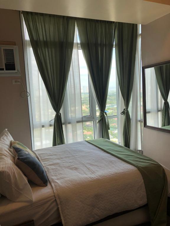 een slaapkamer met een bed en een groot raam bij SAN LORENZO PLACE 2BR 29-E by LARICO in Manilla