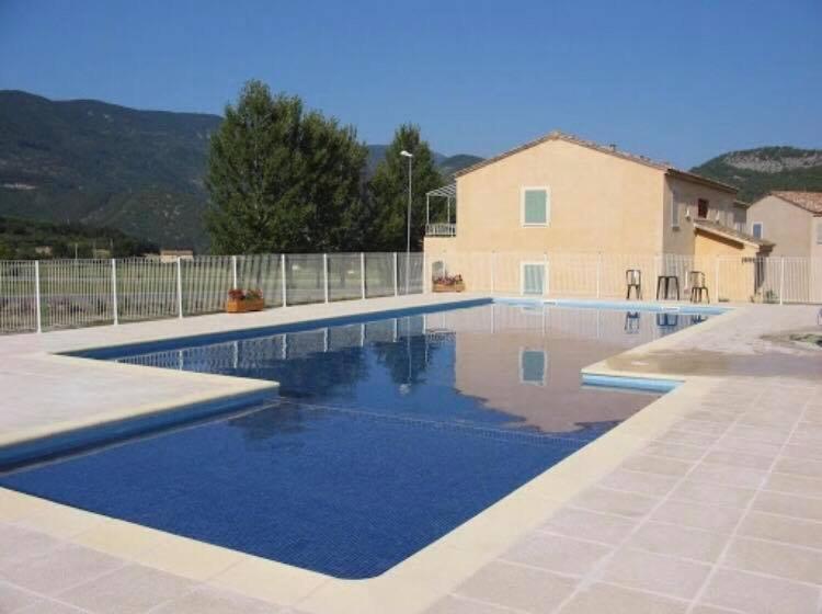 a swimming pool in front of a house at La Tour de Guet in Montbrun-les-Bains
