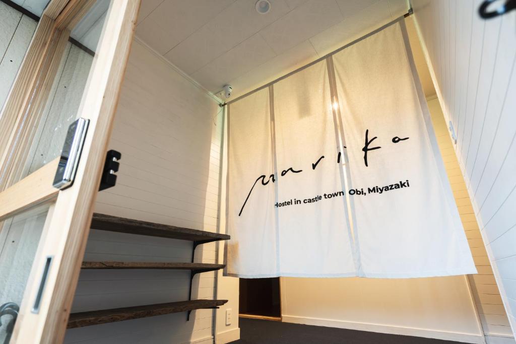 Hostel Marika -ホステルマリカ- في نيتشينان: غرفة مع نافذة عليها علامة على الحائط