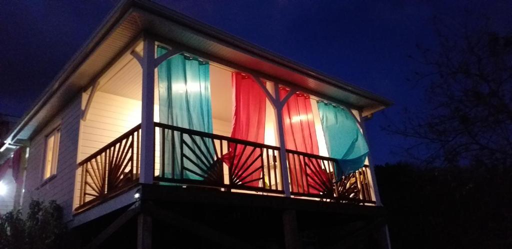 una casa con cortinas coloridas en el balcón por la noche en bel ti kay, en Les Anses-dʼArlet