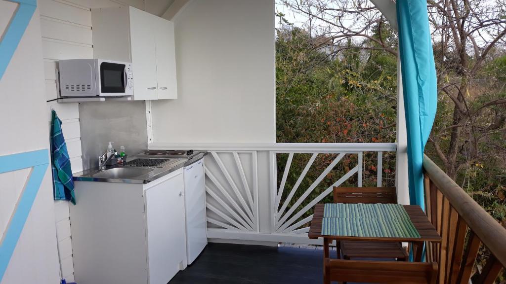 a kitchen with a sink and a microwave on a balcony at bel ti kay in Les Anses-dʼArlets