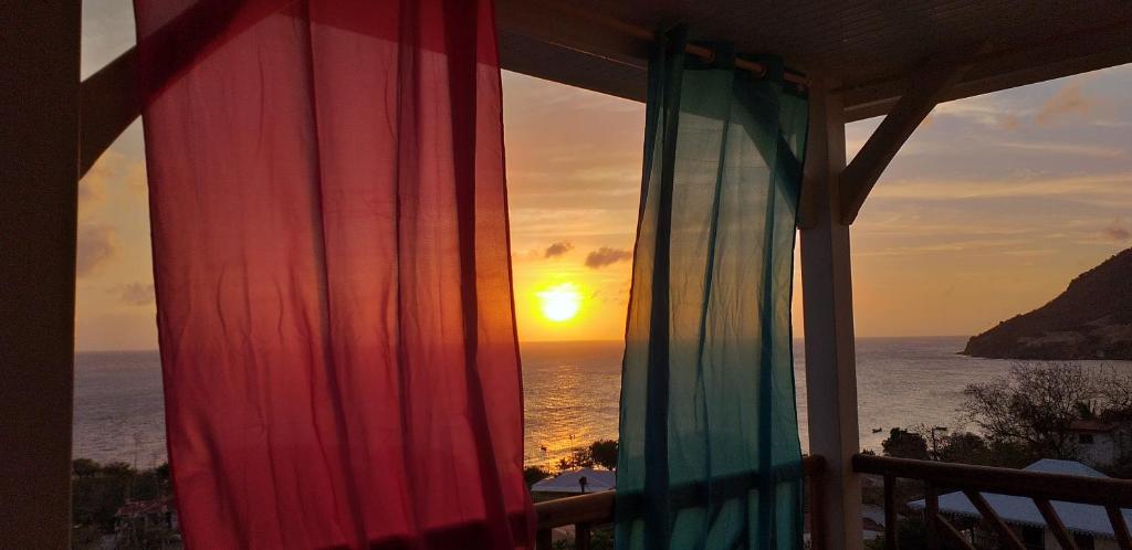 a view of the ocean from a window with the sunset at bel ti kay in Les Anses-dʼArlets