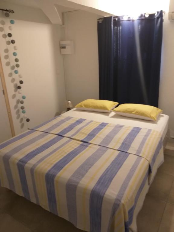 ein Schlafzimmer mit einem Bett mit einer blau-gelben gestreiften Decke in der Unterkunft TI PANNYE in Deshaies