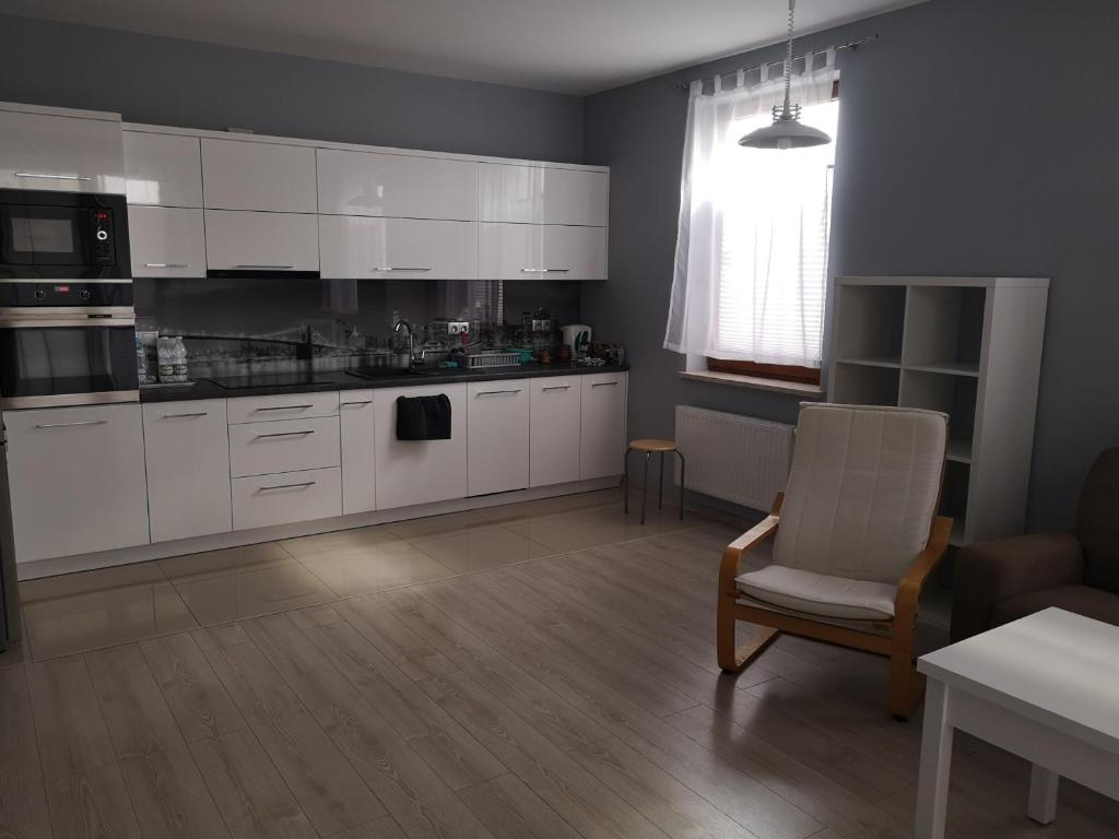 a kitchen with white cabinets and a chair and a table at Apartament Południowy in Radom