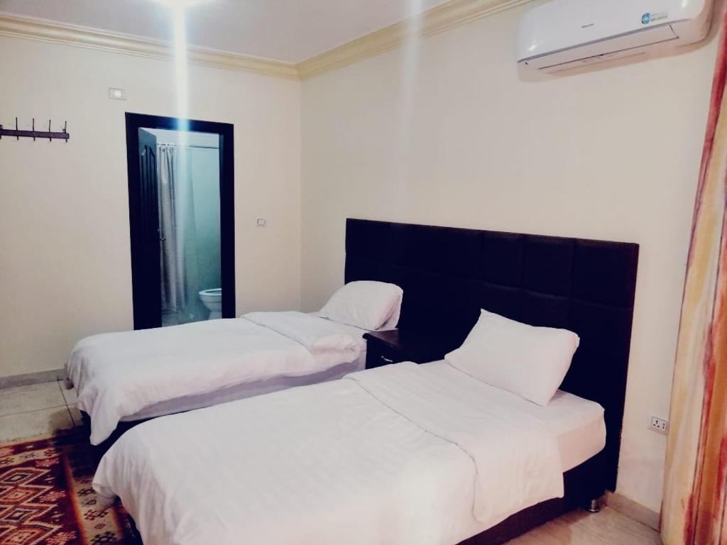 duas camas num quarto com lençóis brancos em Al haramain Furnished Apartments em Amã
