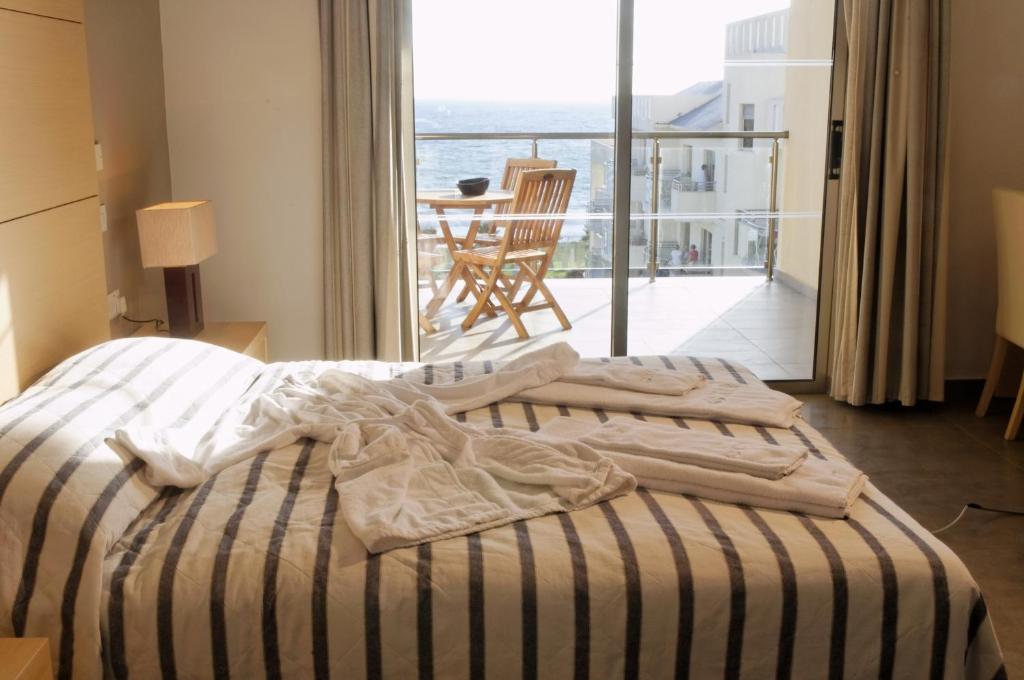 a bedroom with a bed and a view of the ocean at Capital Coast Resort And Spa in Paphos