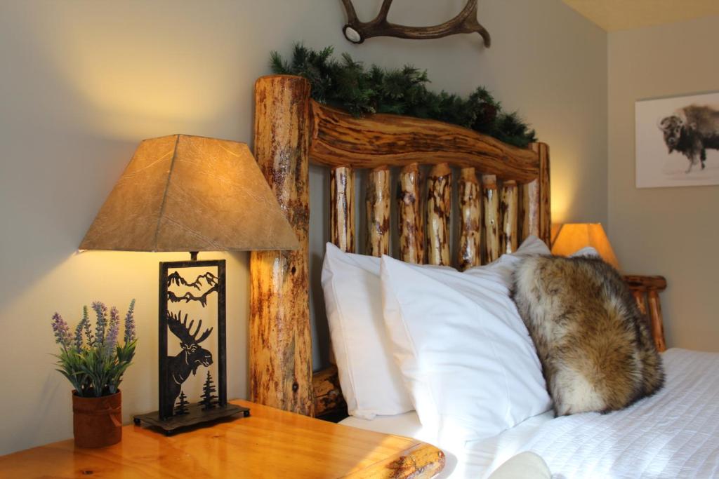 a bed with a wooden headboard and a table with a lamp at The Evergreen in West Yellowstone