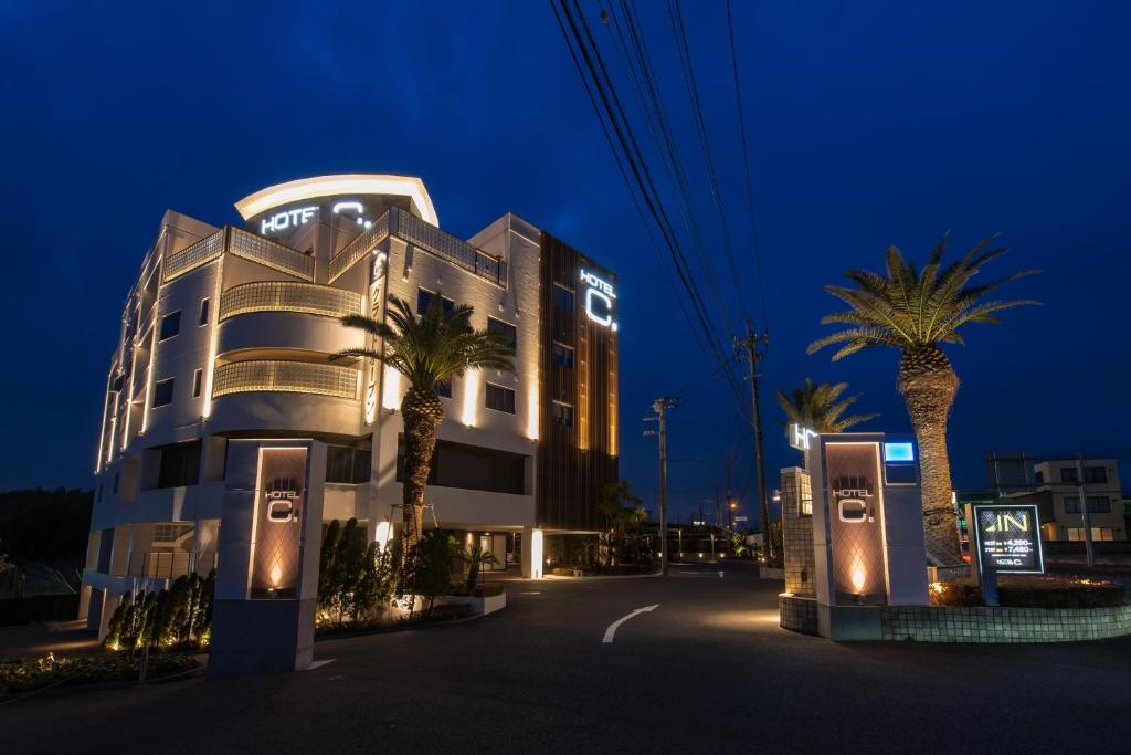 een gebouw met palmbomen er 's nachts voor bij Hotel C. Chiba Shiroi in Shiroi