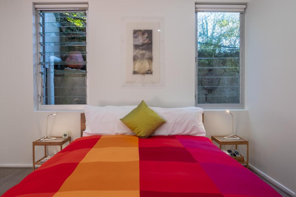um quarto com uma cama colorida e 2 janelas em Bondi Lock-Down Retreat, The Cute Place To Put Up Your Feet em Sidney