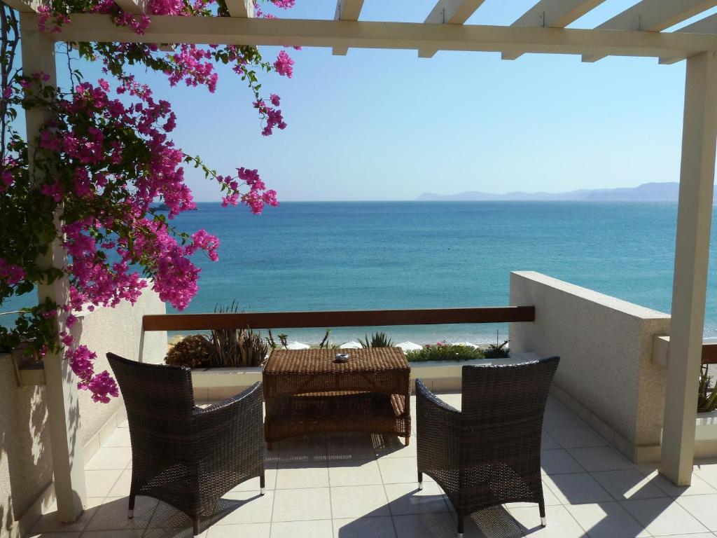 eine Terrasse mit einem Tisch, Stühlen und Meerblick in der Unterkunft Sitia Bay in Sitia