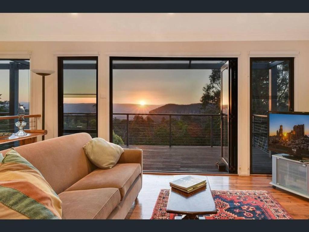 een woonkamer met een bank, een tv en een balkon bij Narrow Neck Views - Peaceful 4 Bedroom Home with Stunning Views! in Katoomba