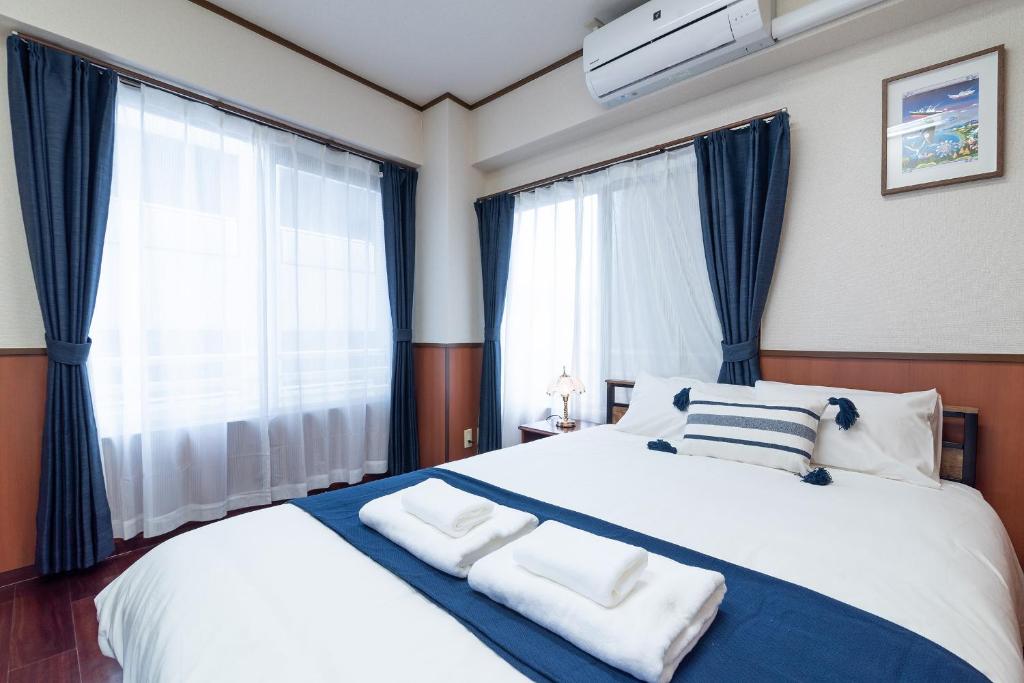 a bedroom with a large bed with blue curtains at Uhome Iriya Apartment in Tokyo