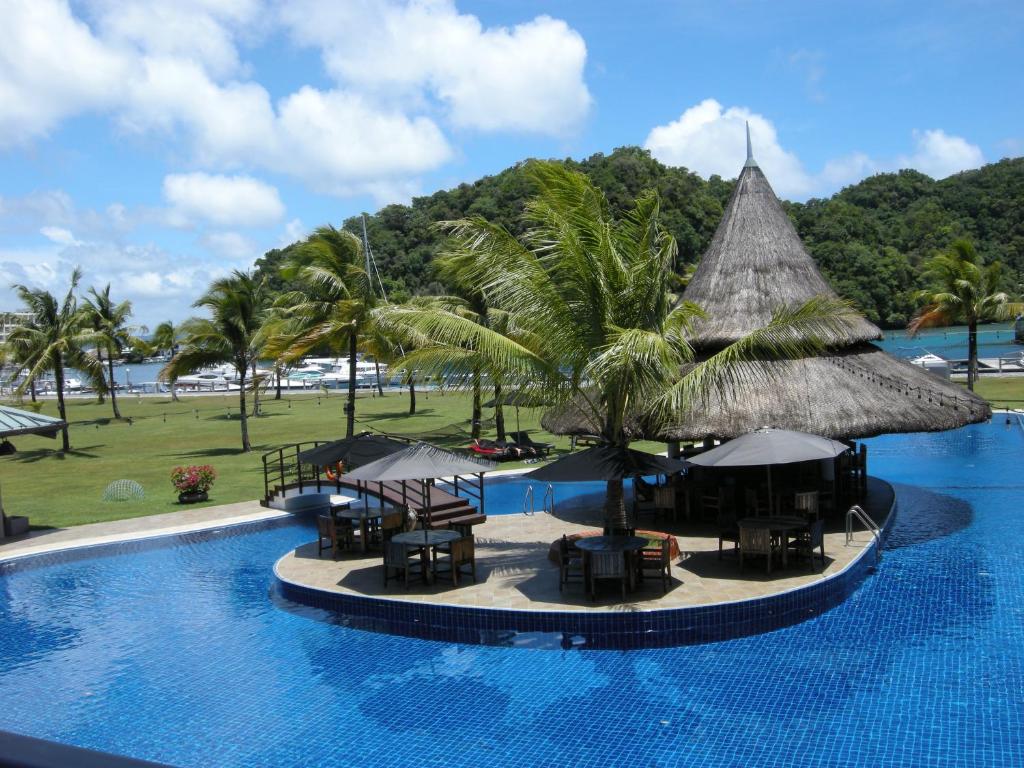 a resort with a pool with tables and umbrellas at Cove Resort Palau in Koror