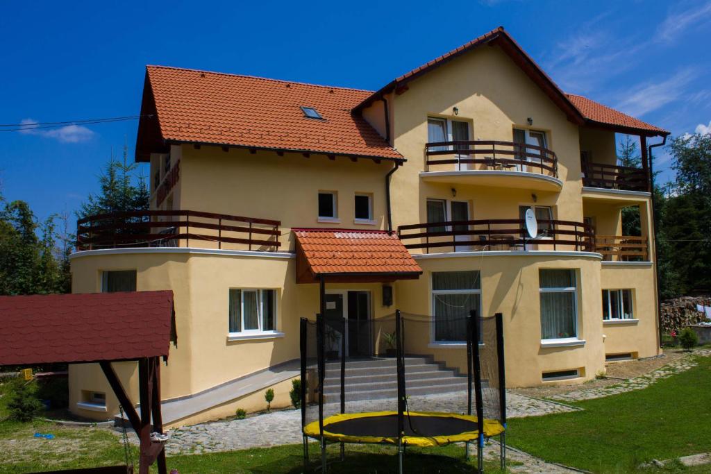 a large yellow building with red roof at Pension Belmonte in Sâmbăta de Sus