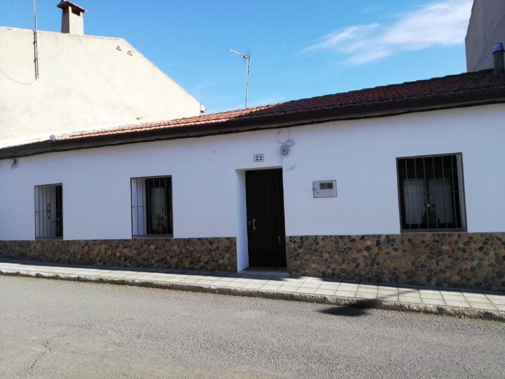 a white building with a black door on a street at Casa Simona in Navas de Estena