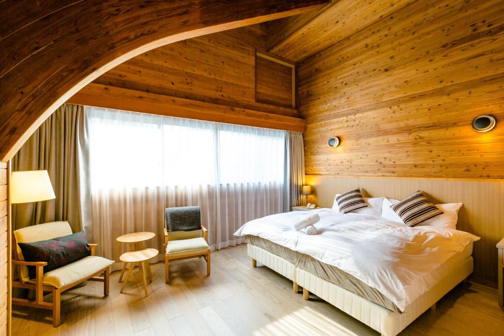 a bedroom with a bed and a wooden wall at Wadano Gateway Suites & Apartments in Hakuba