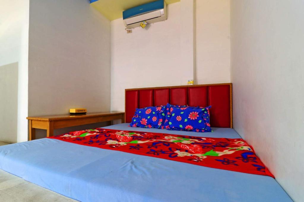 um quarto com uma cama com uma cabeceira vermelha e lençóis azuis em Hotel Rembulan em Tebingtinggi