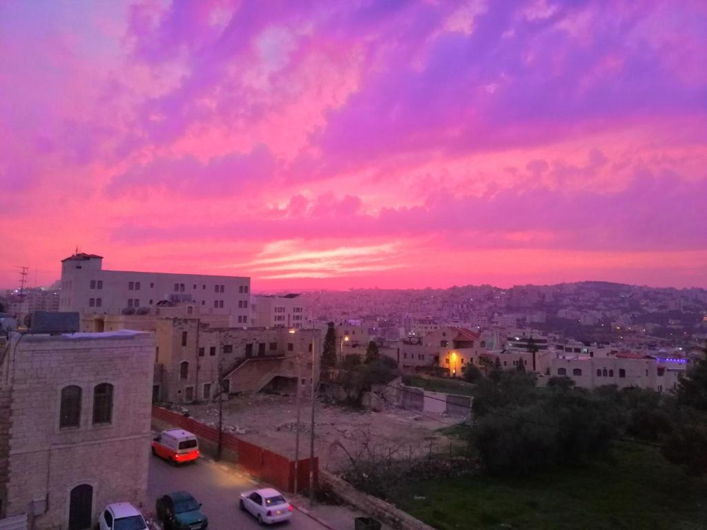 un tramonto su una città con edifici e auto di Bunksurfing Hostel a Bethlehem