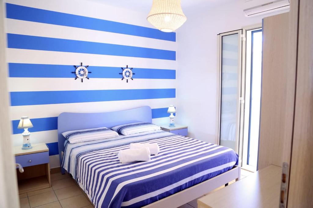 ein blau-weißes Schlafzimmer mit einem Bett mit blauen und weißen Streifen in der Unterkunft La stella di Montalbano con parcheggio privato in Punta Secca
