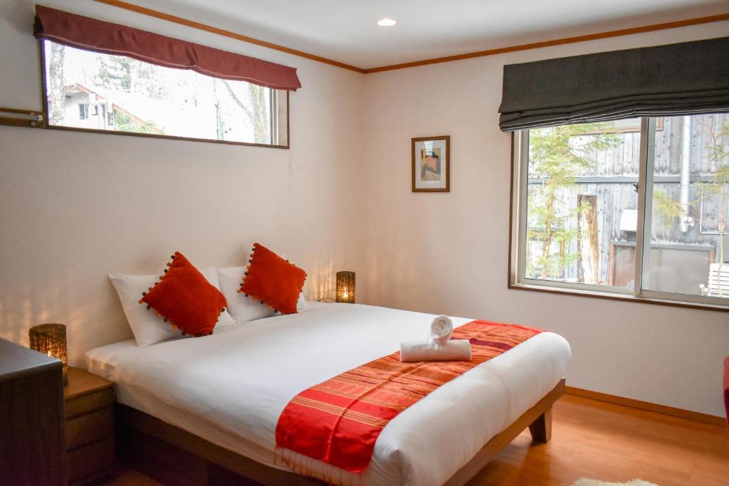 um quarto com uma grande cama branca com almofadas vermelhas em Mojo Lodge Hakuba em Hakuba