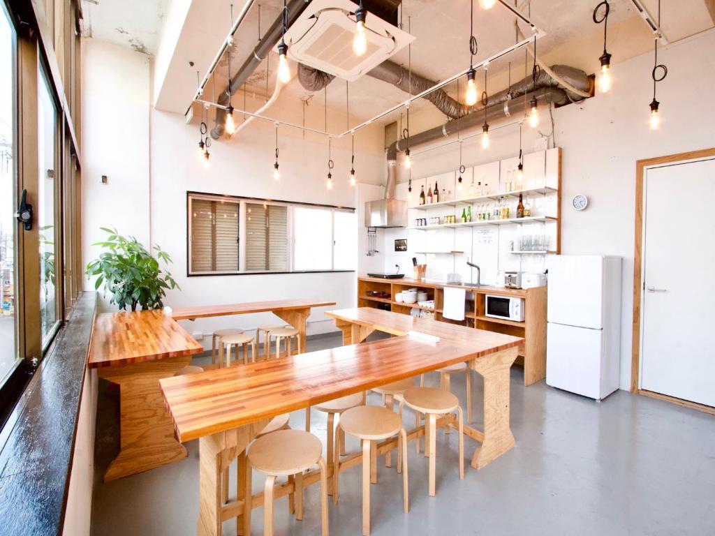 a kitchen with a long wooden table and stools at Ishigaki Guesthouse HIVE in Ishigaki Island
