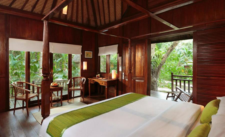 a bedroom with a large bed and a table and chairs at The Barefoot At Havelock in Havelock Island