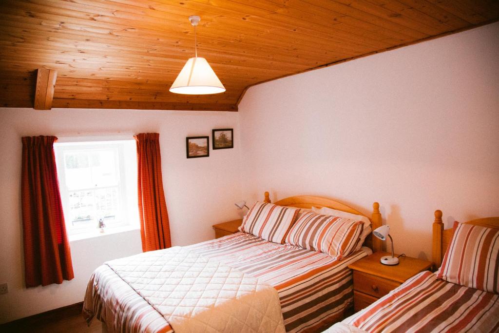 een slaapkamer met 2 bedden en een raam bij Beagh Cottage in Ardara