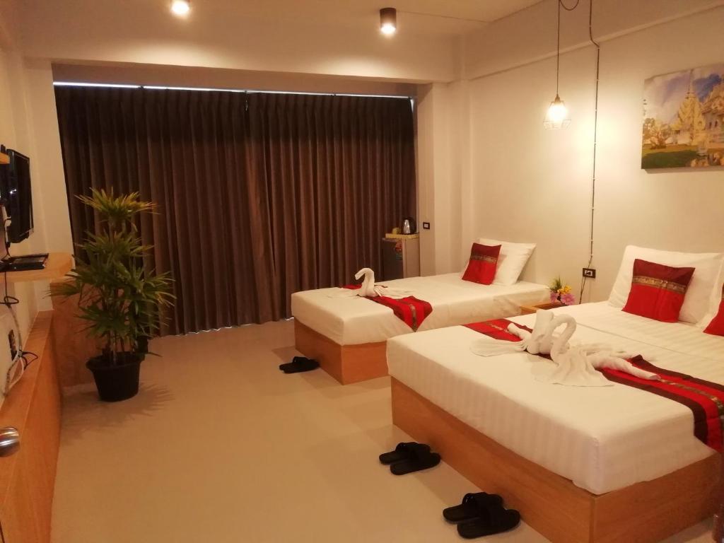 Cette chambre comprend deux lits et une télévision. dans l'établissement Little Lanna Guesthouse, à Chiang Mai