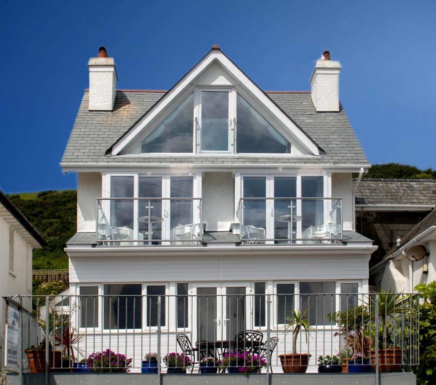 uma casa branca com uma varanda com cadeiras em Seaview em Looe