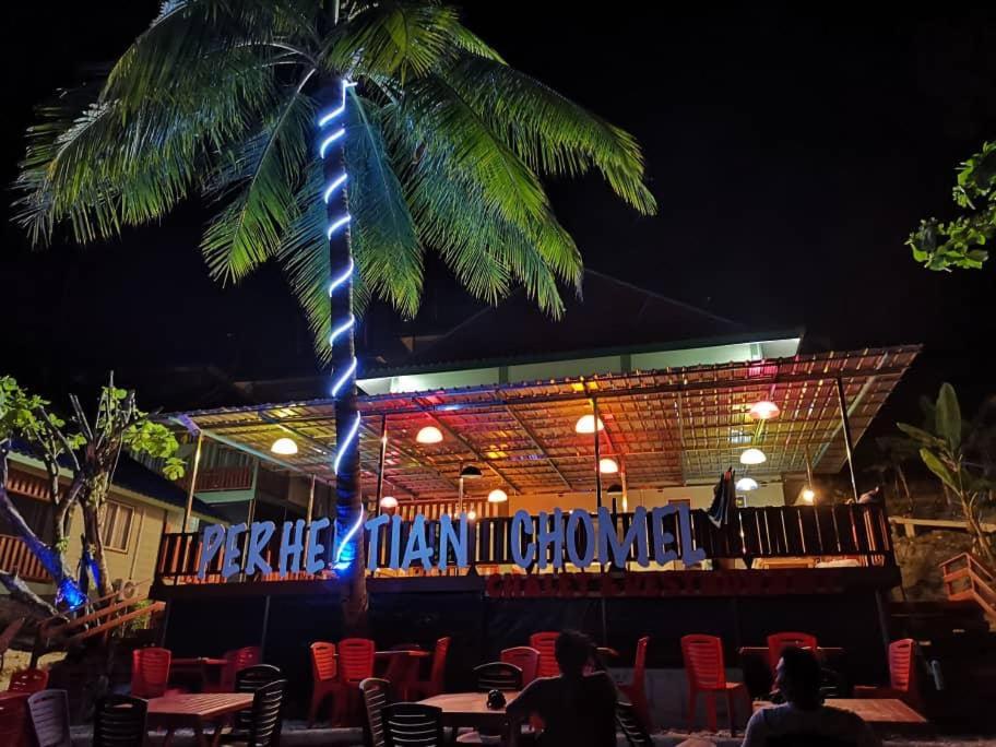 a palm tree in front of a restaurant at night at Perhentian Chomel Chalet in Perhentian Island
