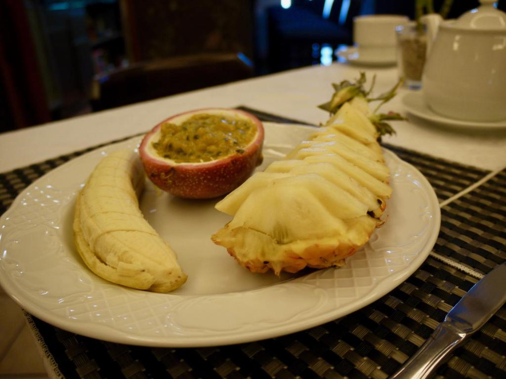 a white plate with a peeled banana and an orange at Hotel Ida Inés in Frontera