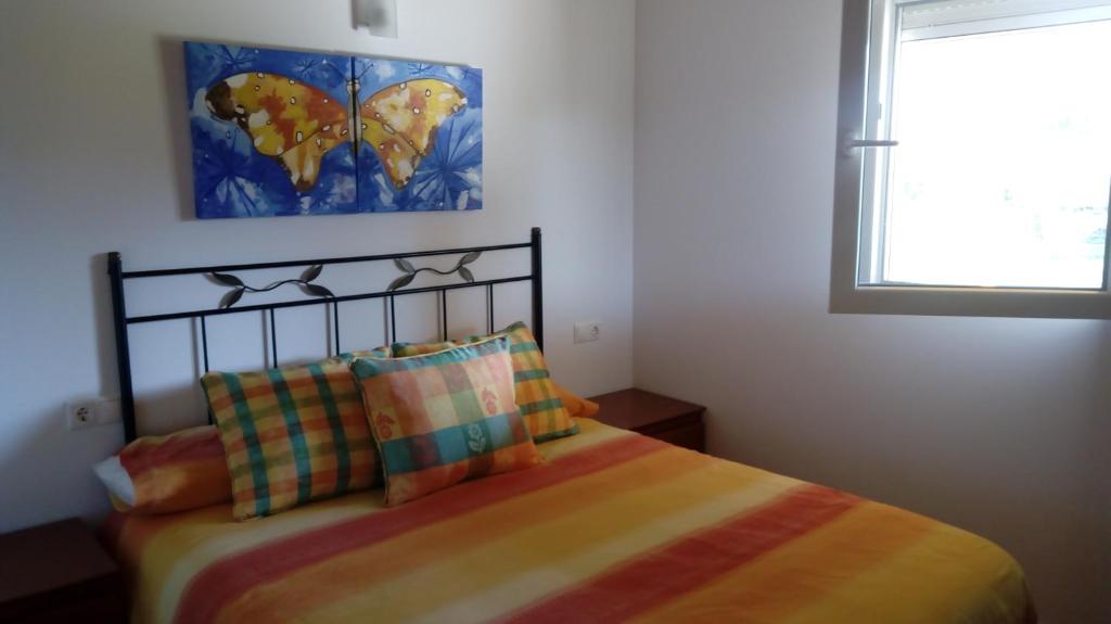 um quarto com uma cama com lençóis coloridos e uma janela em Casa individual barrio las escuelas em Hazas de Cesto